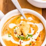 A bowl of creamy carrot and lentil soup with a drizzle of cream on top.